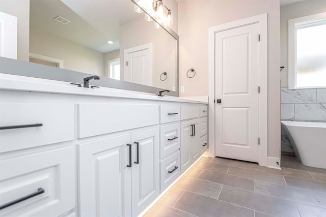 bathroom featuring a bathing tub, tile patterned flooring, and vanity