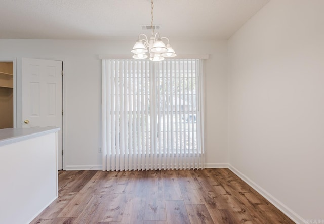 unfurnished dining area with a chandelier and light hardwood / wood-style floors