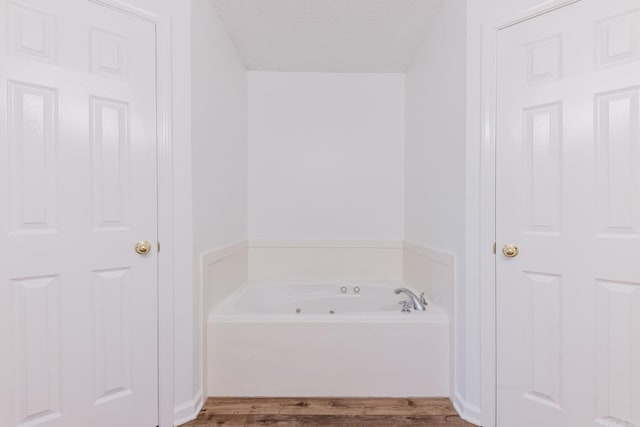 bathroom featuring a tub, a textured ceiling, and hardwood / wood-style flooring