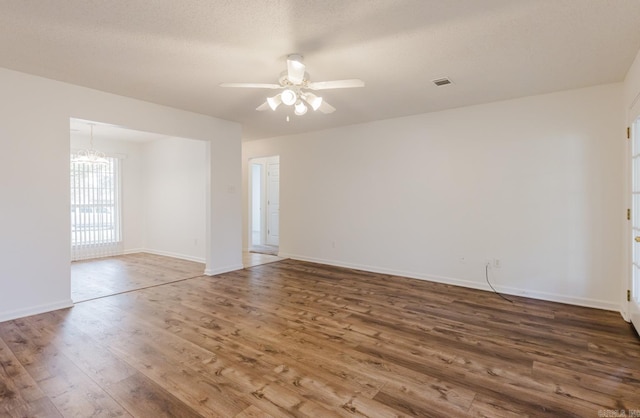 unfurnished room featuring a textured ceiling, ceiling fan with notable chandelier, and dark hardwood / wood-style floors