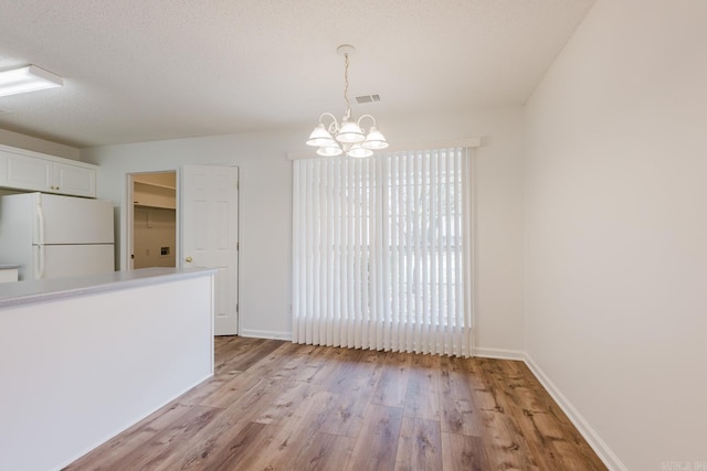 interior space featuring a notable chandelier, a textured ceiling, and light hardwood / wood-style flooring