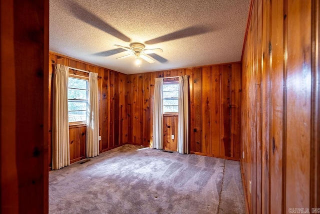 713 N Spring St, Searcy, AR 72143 - unfurnished room with healthy amount of natural light, a textured ceiling, ceiling fan, carpet floors, and wood walls