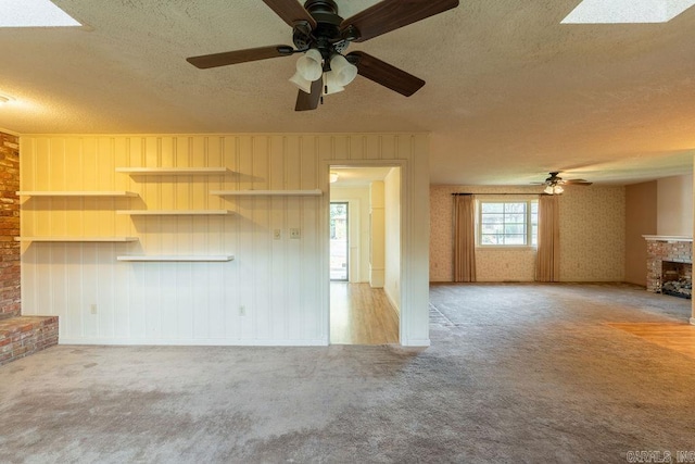713 N Spring St, Searcy, AR 72143 - unfurnished living room with a brick fireplace, a textured ceiling, a ceiling fan, and carpet floors