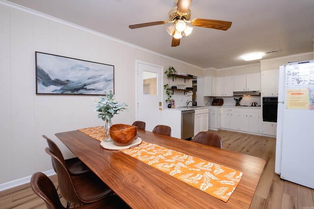 dining room featuring crown molding, sink, ceiling fan, and light wood-type flooring