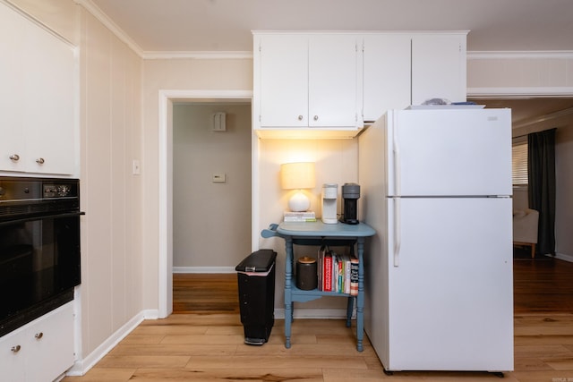 kitchen with white cabinets, oven, white refrigerator, ornamental molding, and light hardwood / wood-style floors