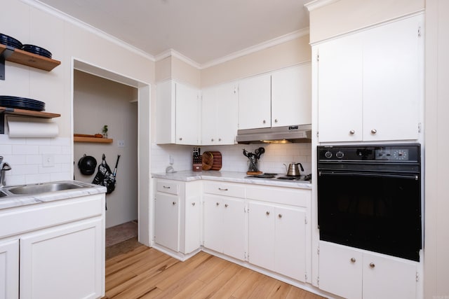 kitchen featuring oven, light wood-type flooring, white cabinetry, and crown molding