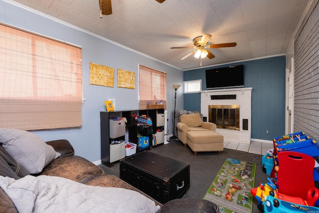 living room featuring ceiling fan, ornamental molding, a textured ceiling, and a brick fireplace