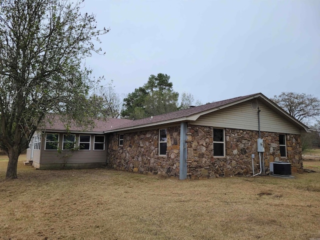 rear view of property with central air condition unit and a yard