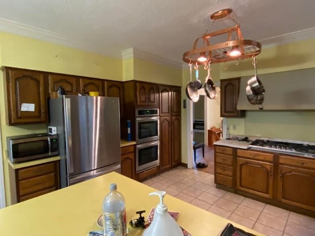 kitchen featuring light tile patterned floors, a textured ceiling, stainless steel appliances, and crown molding