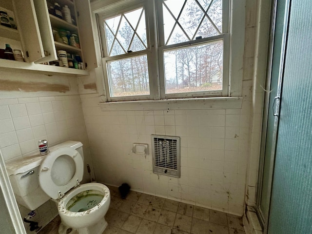 bathroom with toilet, tile walls, and a wealth of natural light