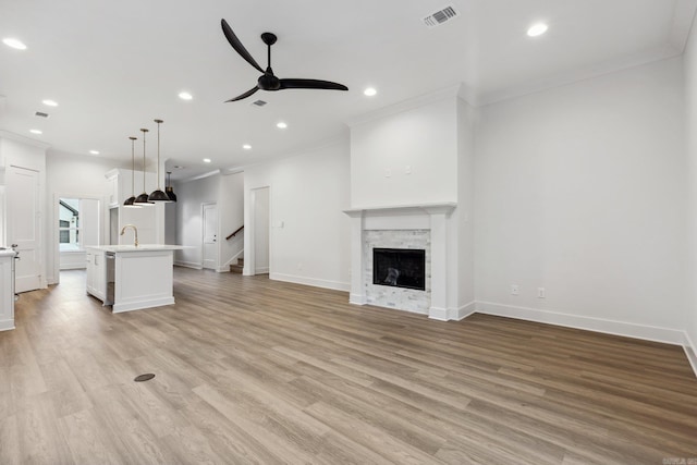 unfurnished living room featuring crown molding, ceiling fan, and light wood-type flooring