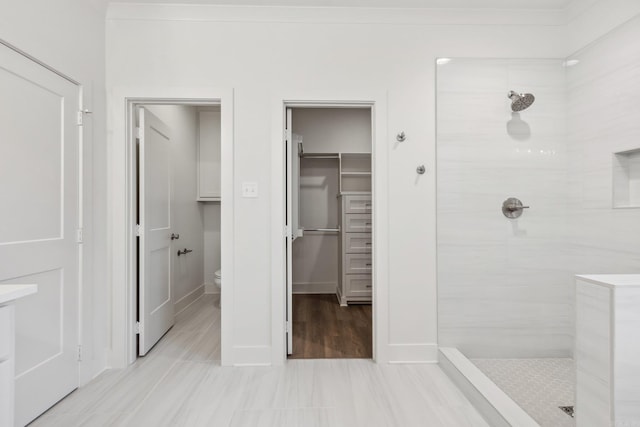 bathroom featuring hardwood / wood-style floors, toilet, and a tile shower