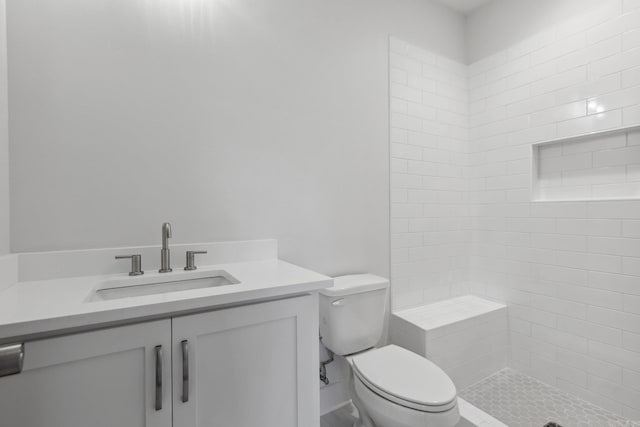 bathroom featuring tiled shower, vanity, and toilet