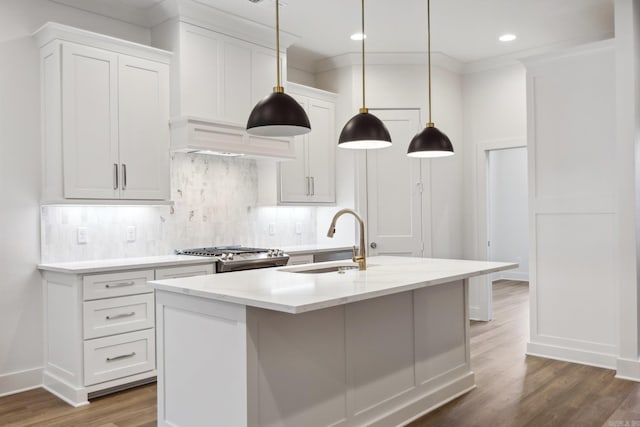 kitchen with a center island with sink, sink, stainless steel range, dark hardwood / wood-style flooring, and white cabinetry