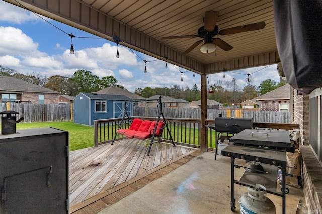 deck with a lawn, ceiling fan, and a storage shed