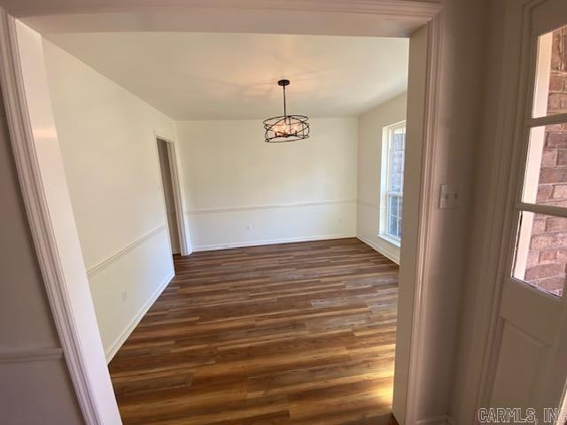 unfurnished dining area with dark hardwood / wood-style floors and an inviting chandelier