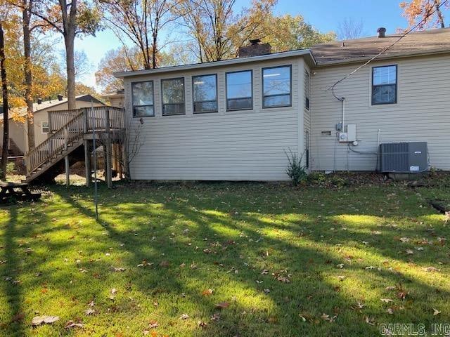 rear view of property with a deck, a yard, and central AC unit