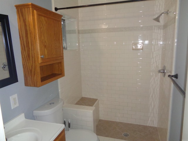 bathroom featuring toilet, vanity, and tiled shower