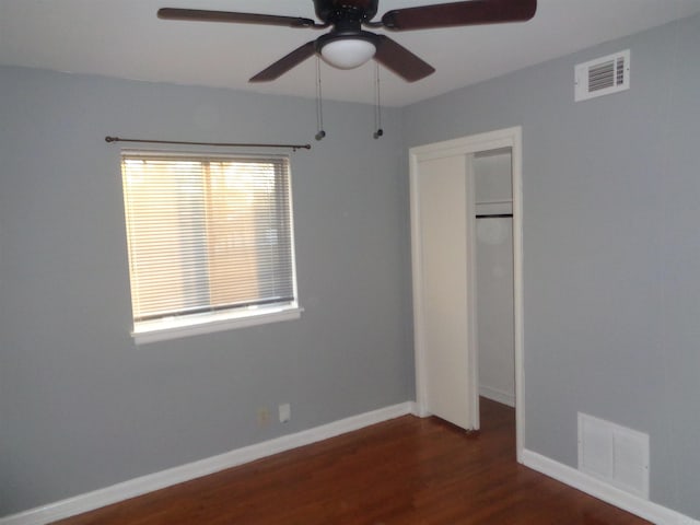 unfurnished bedroom featuring multiple windows, dark hardwood / wood-style flooring, a closet, and ceiling fan