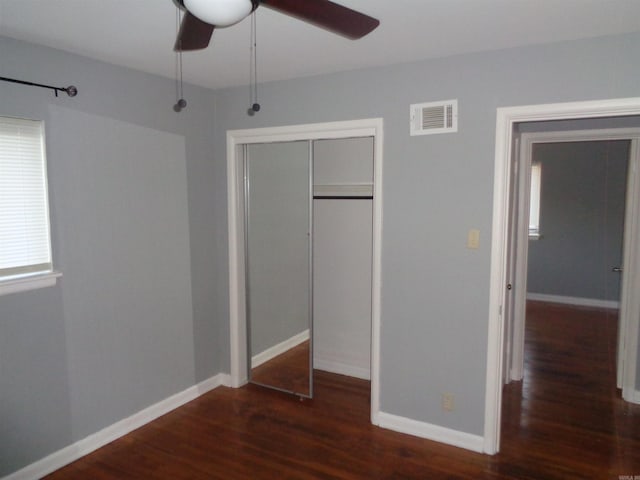 unfurnished bedroom with ceiling fan, a closet, and dark wood-type flooring