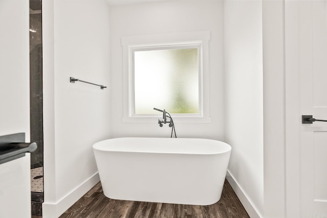 bathroom with wood-type flooring and a bath