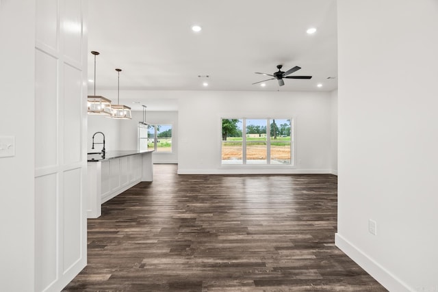 unfurnished living room featuring dark hardwood / wood-style floors, ceiling fan, and sink