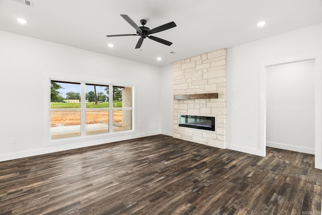 unfurnished living room featuring ceiling fan, a stone fireplace, and dark hardwood / wood-style flooring