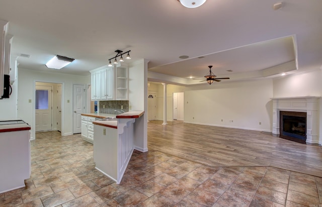 kitchen with kitchen peninsula, a kitchen breakfast bar, light wood-type flooring, backsplash, and white cabinets