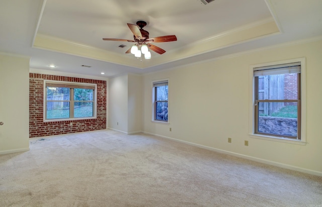 unfurnished room with a raised ceiling, ceiling fan, light colored carpet, and ornamental molding