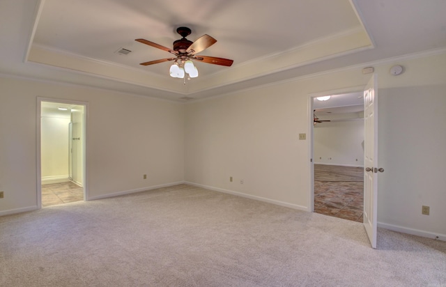 carpeted empty room with a raised ceiling, ceiling fan, and ornamental molding