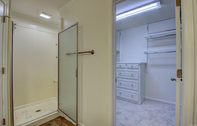 bathroom featuring a shower with shower door and ornamental molding