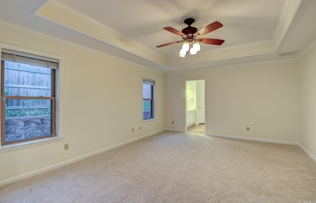 carpeted empty room with a raised ceiling, ceiling fan, and crown molding