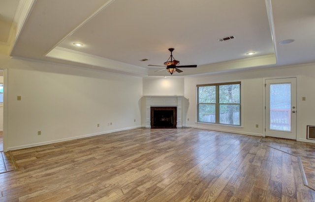 unfurnished living room with hardwood / wood-style floors, a tray ceiling, ceiling fan, and crown molding