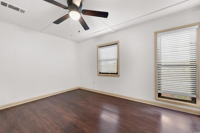 empty room featuring ceiling fan, a healthy amount of sunlight, and dark wood-type flooring