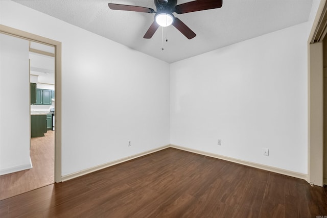 empty room with ceiling fan, dark hardwood / wood-style flooring, and a textured ceiling