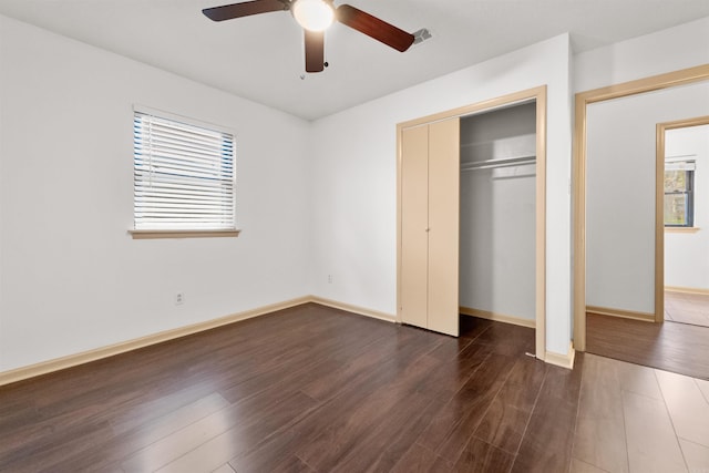 unfurnished bedroom featuring a closet, multiple windows, ceiling fan, and dark hardwood / wood-style flooring