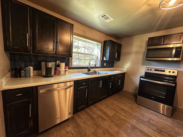 kitchen featuring dark brown cabinetry, sink, hardwood / wood-style floors, and appliances with stainless steel finishes