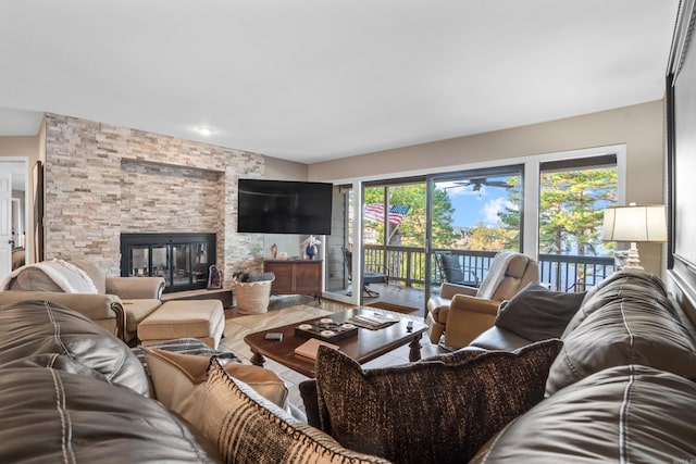 living room with ceiling fan, a stone fireplace, and wood-type flooring