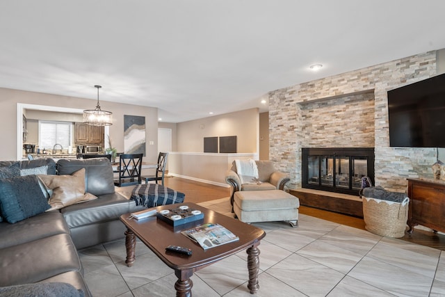 living room with a stone fireplace and an inviting chandelier