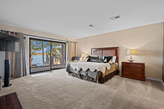 carpeted bedroom featuring a water view and access to outside