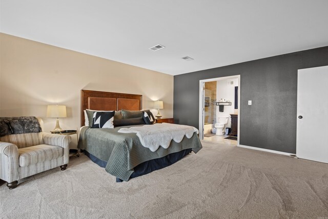 bedroom featuring light carpet and connected bathroom