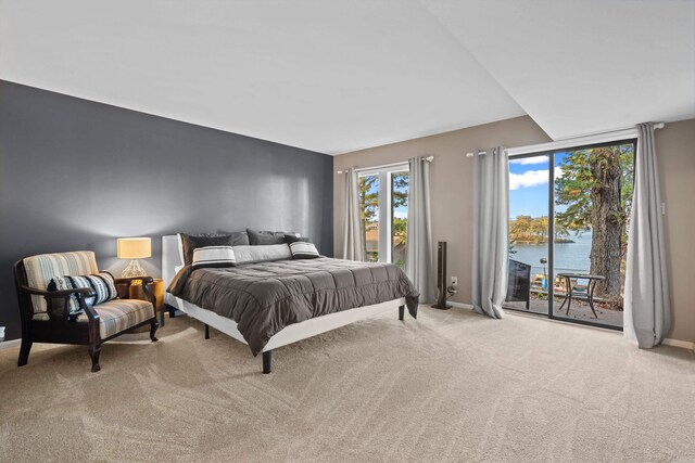 bedroom featuring access to outside, a water view, and light colored carpet