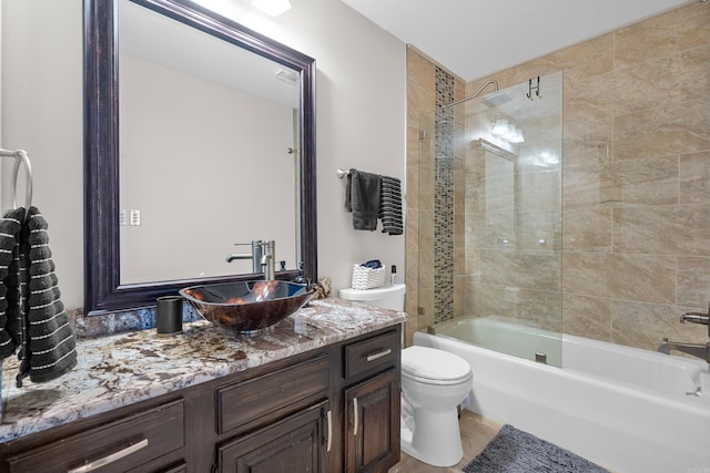 full bathroom featuring vanity, tiled shower / bath combo, and toilet