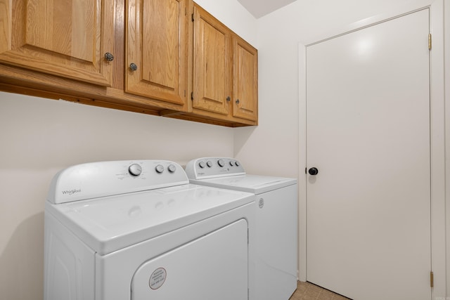 clothes washing area with washer and dryer and cabinets