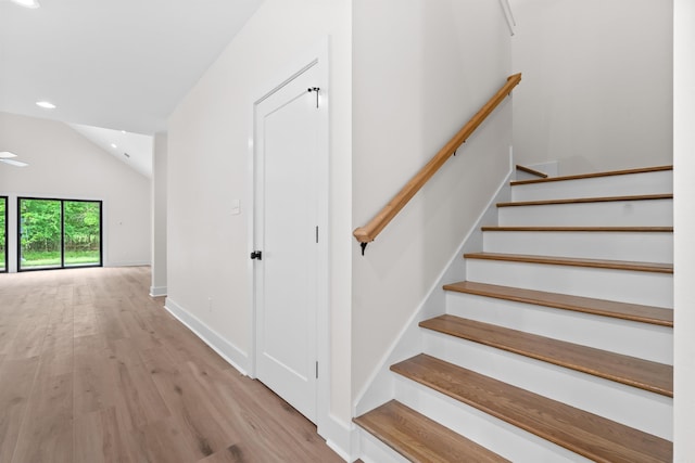 stairs featuring hardwood / wood-style flooring and vaulted ceiling