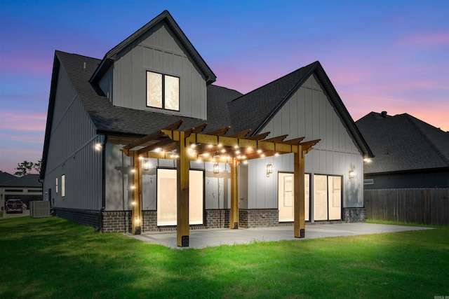 back house at dusk with a lawn, a pergola, a patio, and central AC