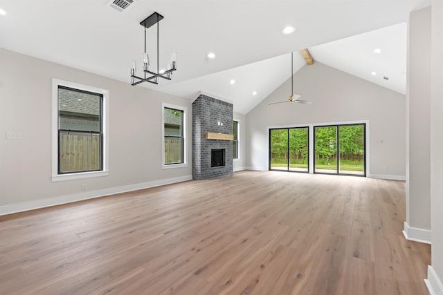 unfurnished living room featuring a healthy amount of sunlight, a fireplace, high vaulted ceiling, and light hardwood / wood-style flooring