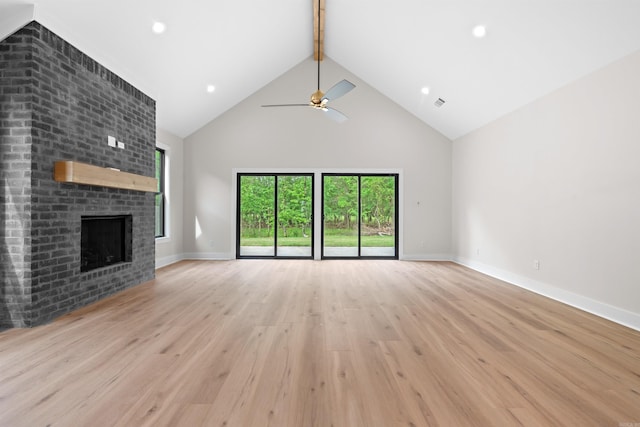 unfurnished living room with a fireplace, ceiling fan, light hardwood / wood-style flooring, and high vaulted ceiling