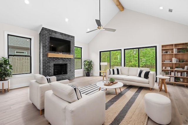 living room with a brick fireplace, ceiling fan, beam ceiling, high vaulted ceiling, and light hardwood / wood-style flooring