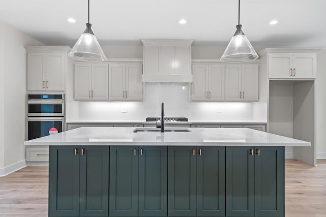 kitchen with a center island with sink, decorative light fixtures, and white cabinetry